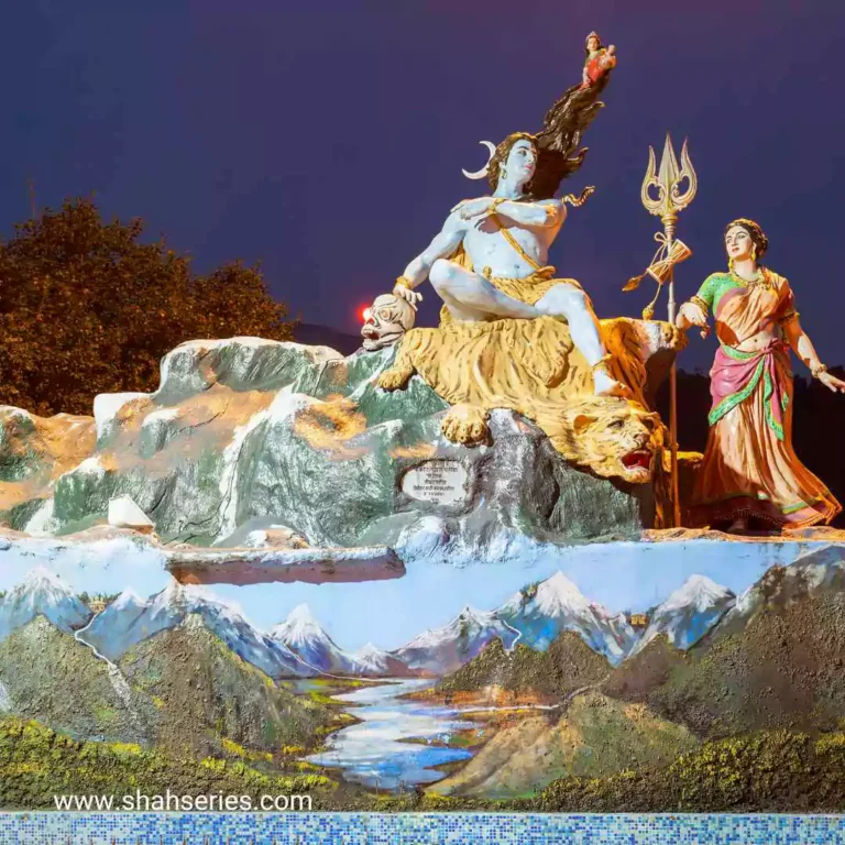 The image includes a painting of a sky, tree, statue of Shiv Parvati, outdoor scenery, and mountains.